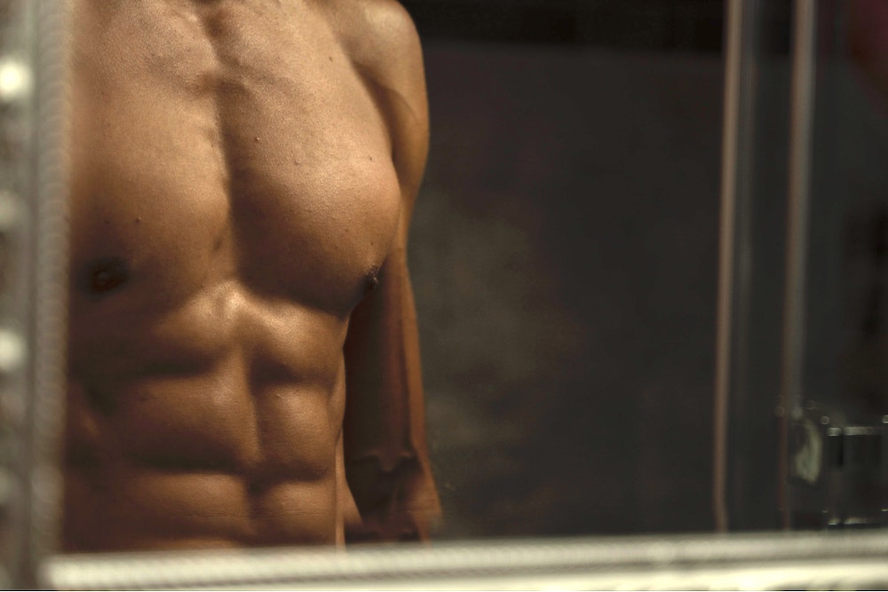 man with well built body facing the mirror